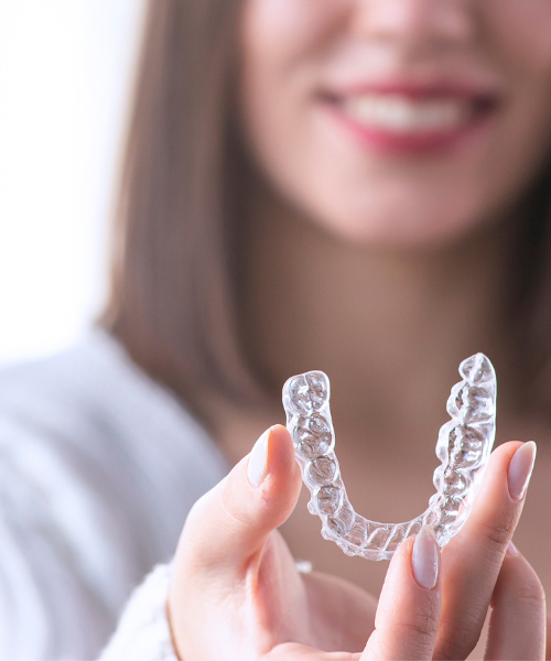 woman holding up invisalign clear aligners | Oak Point TX 75068