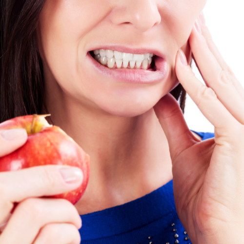 A woman in a blue shirt is holding an apple in her hand