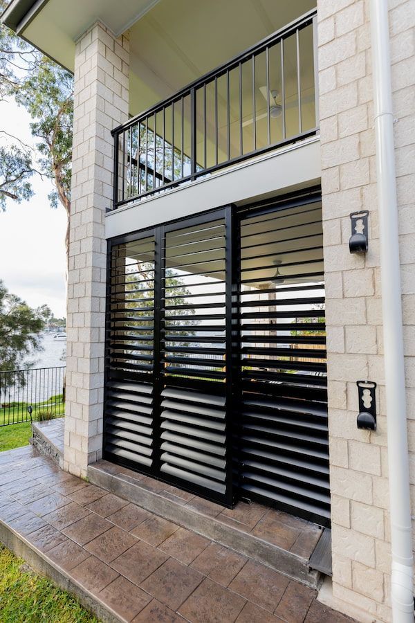 A White Brick Building with a Black Balcony and Black Shutters — New Blinds and Shutters in Maryland, NSW