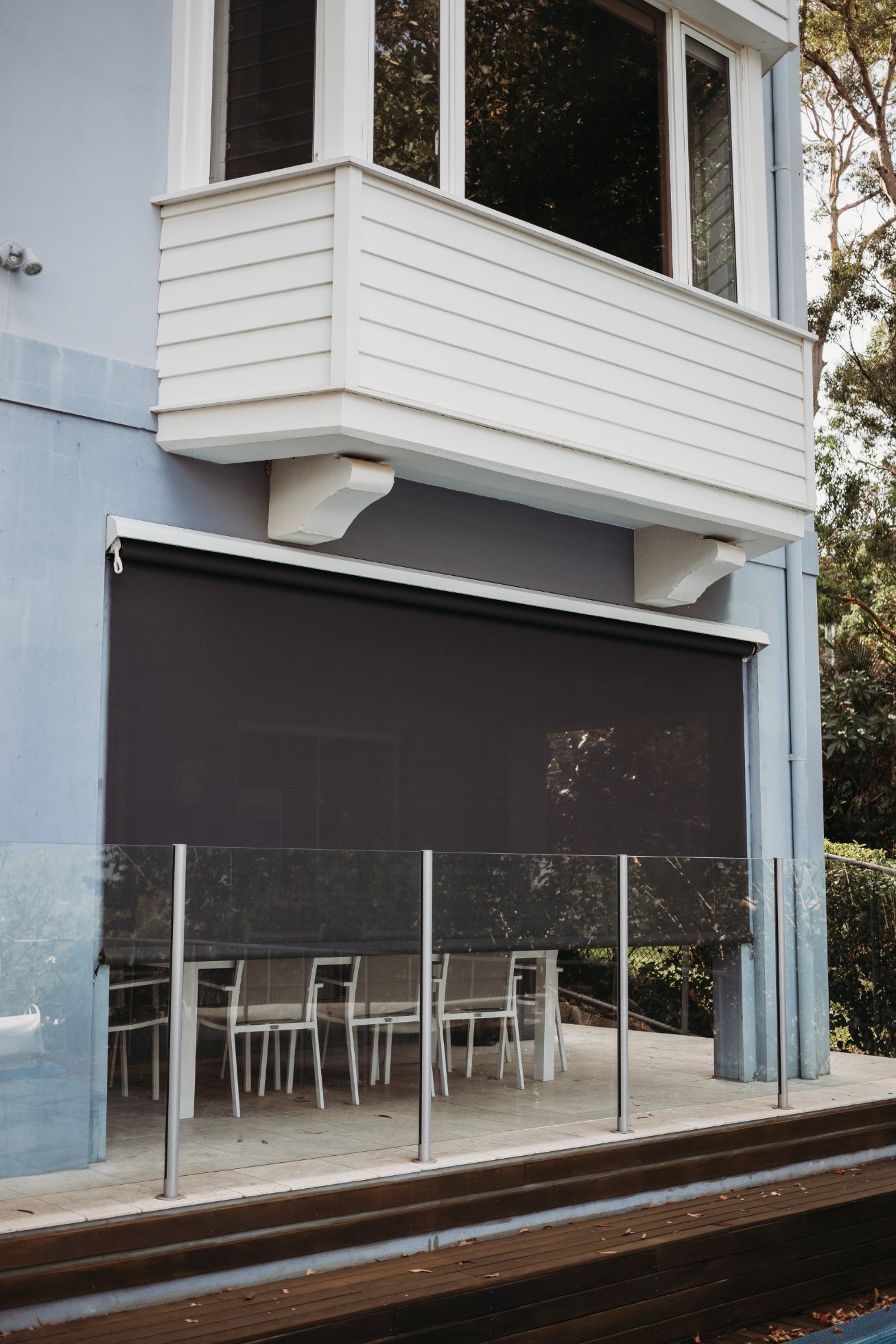 A Blue House with A Balcony and A Patio with Tables and Chairs  — New Blinds and Shutters in Maryland, NSW