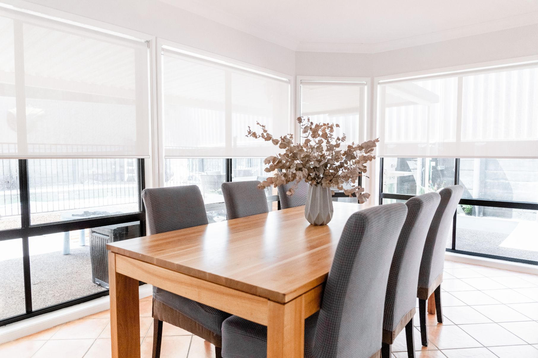 A Dining Room with A Wooden Table and Chairs and A Vase of Flowers on The Table — New Blinds and Shutters in Maryland, NSW