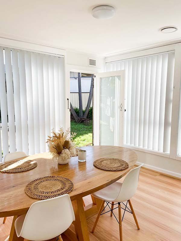 A Dining Room with A Wooden Table and Chairs and White Blinds — New Blinds and Shutters in Maryland, NSW
