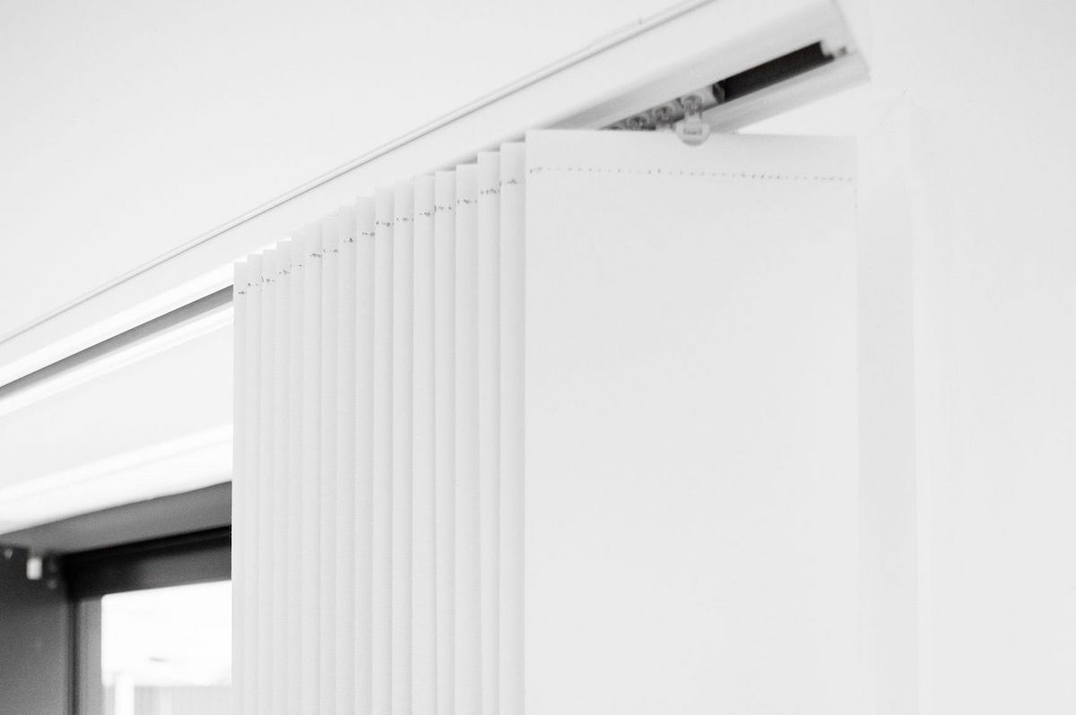 A Close up Of a White Vertical Blind on A Window — New Blinds and Shutters in Maryland, NSW