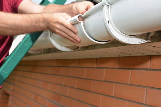Worker repairing white vinyl gutter