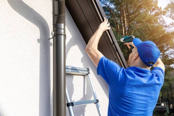Worker fixing residential roof gutters