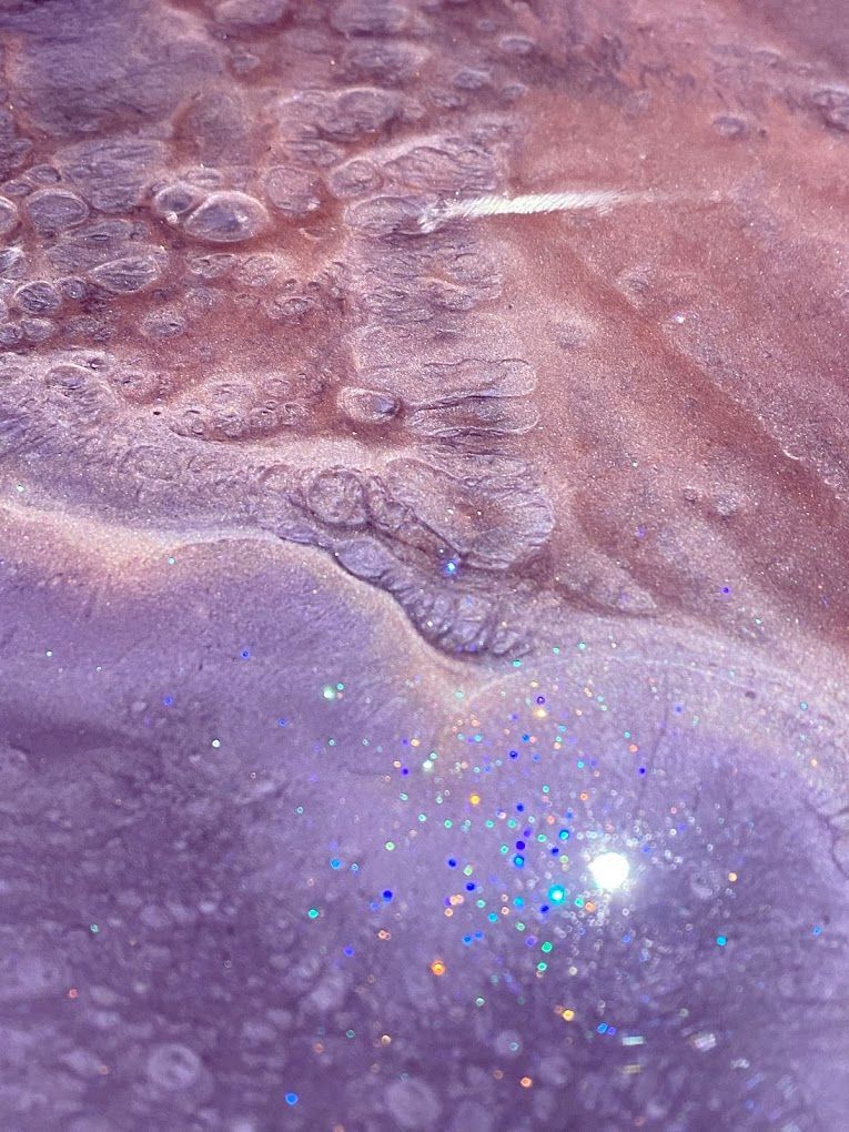 A close up of a purple and pink painting with glitter.