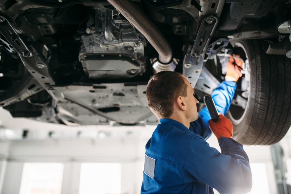 A Mechanic Is Working Under a Car in A Garage — Coastal Mechanical Solutions In Albion Park Rail, NSW