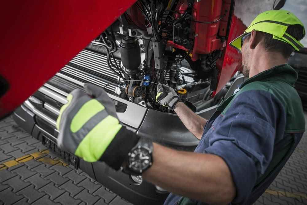 A Man Is Working on The Underside of A Truck — Coastal Mechanical Solutions In Albion Park Rail, NSW