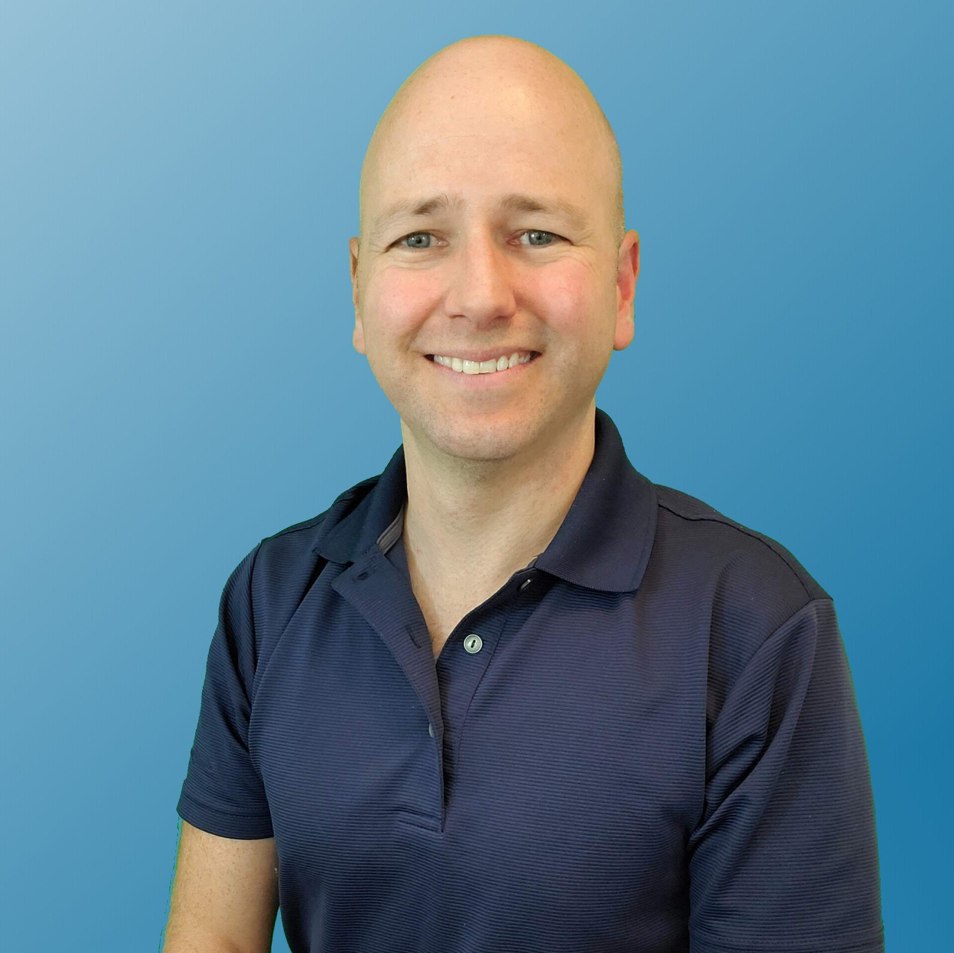 Smiling bald man in navy polo shirt, posed against a blue gradient backdrop.