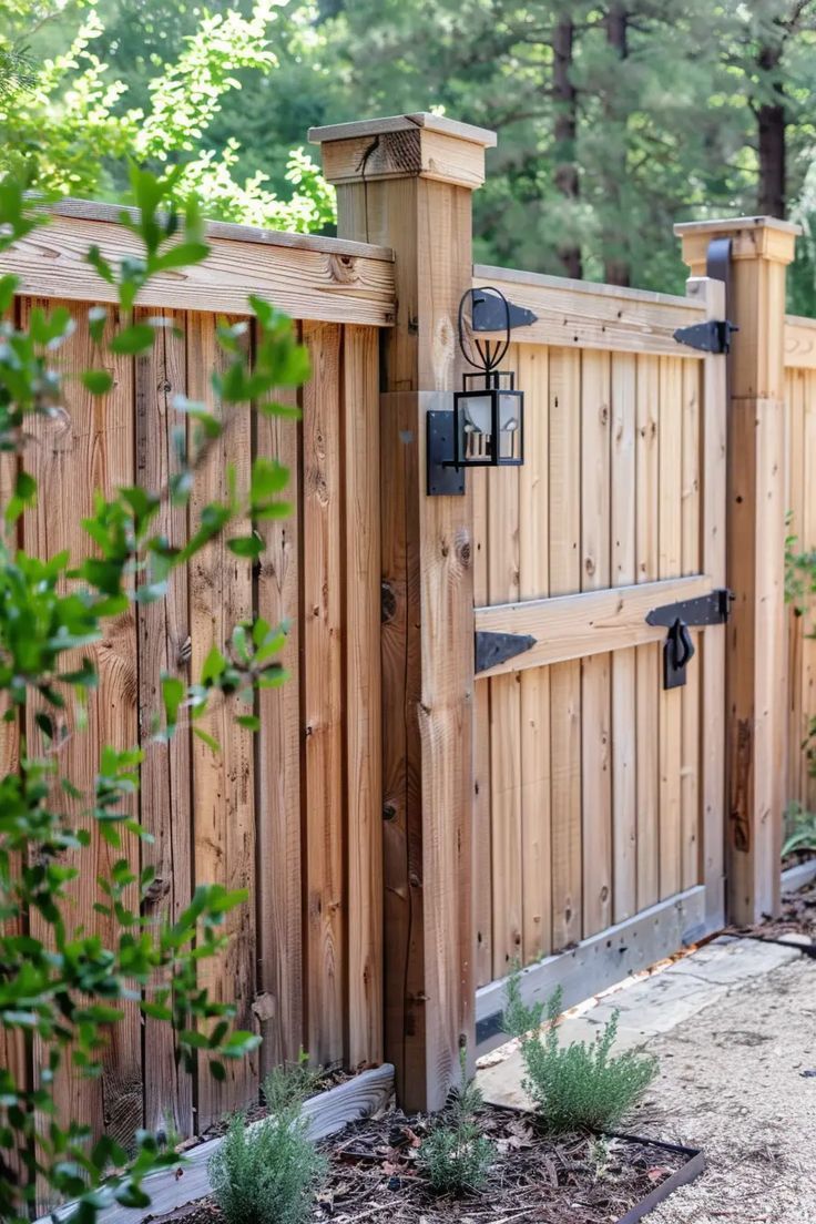 Wooden garden gate with black hardware in a fenced yard, surrounded by greenery.
