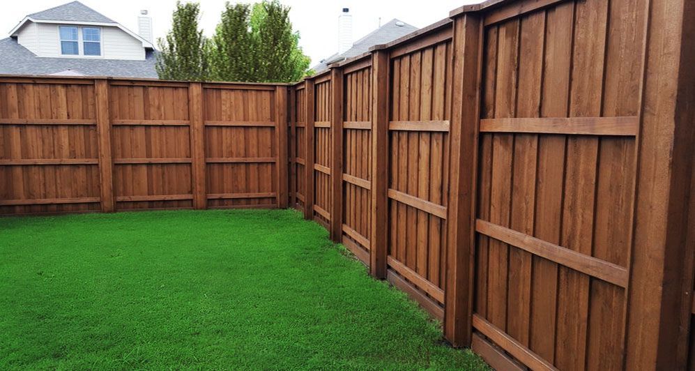 Backyard with bright green grass and tall wooden privacy fence