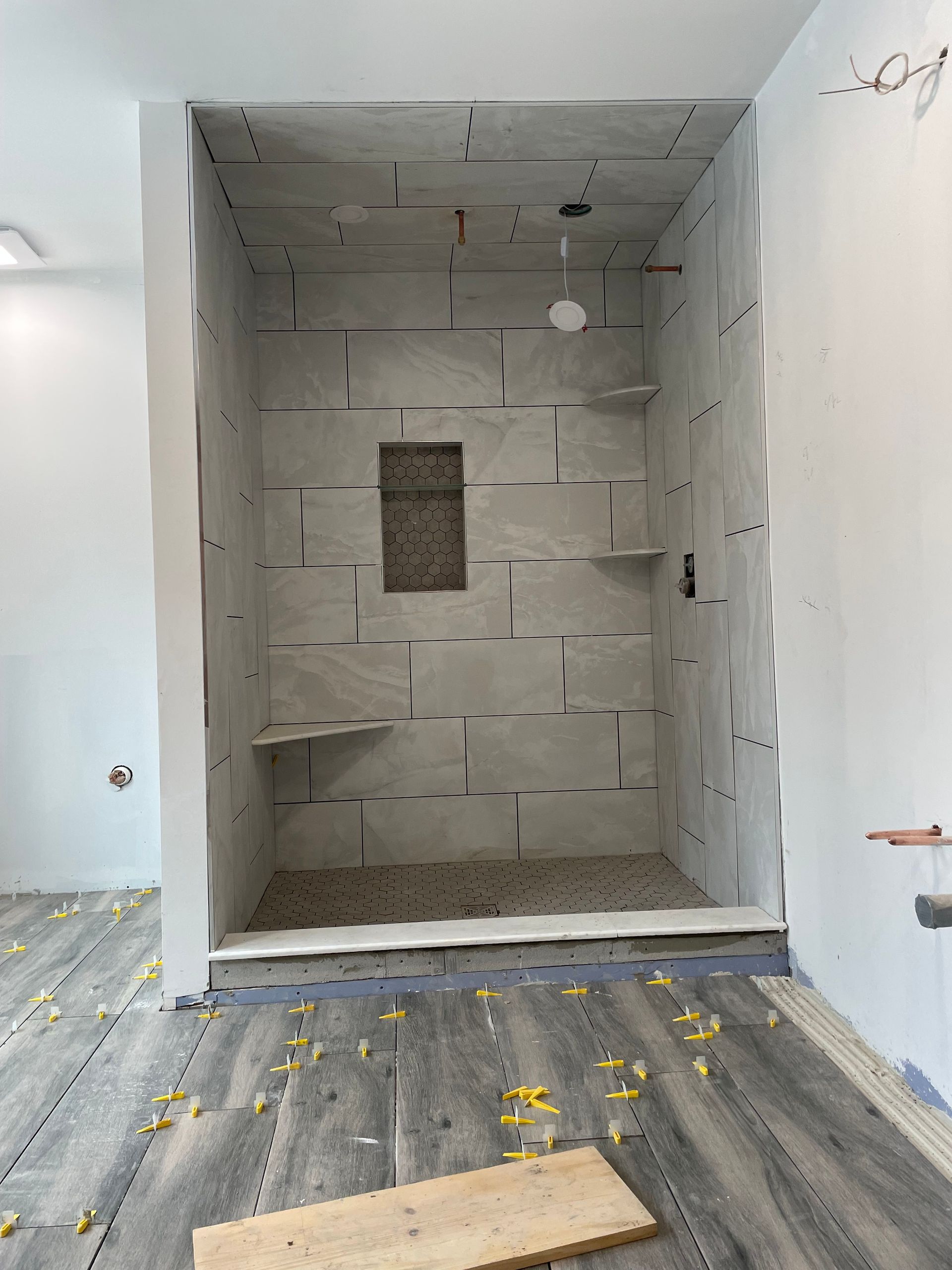 Empty recessed wall niche under renovation in a white room with unfinished cinderblock backing.