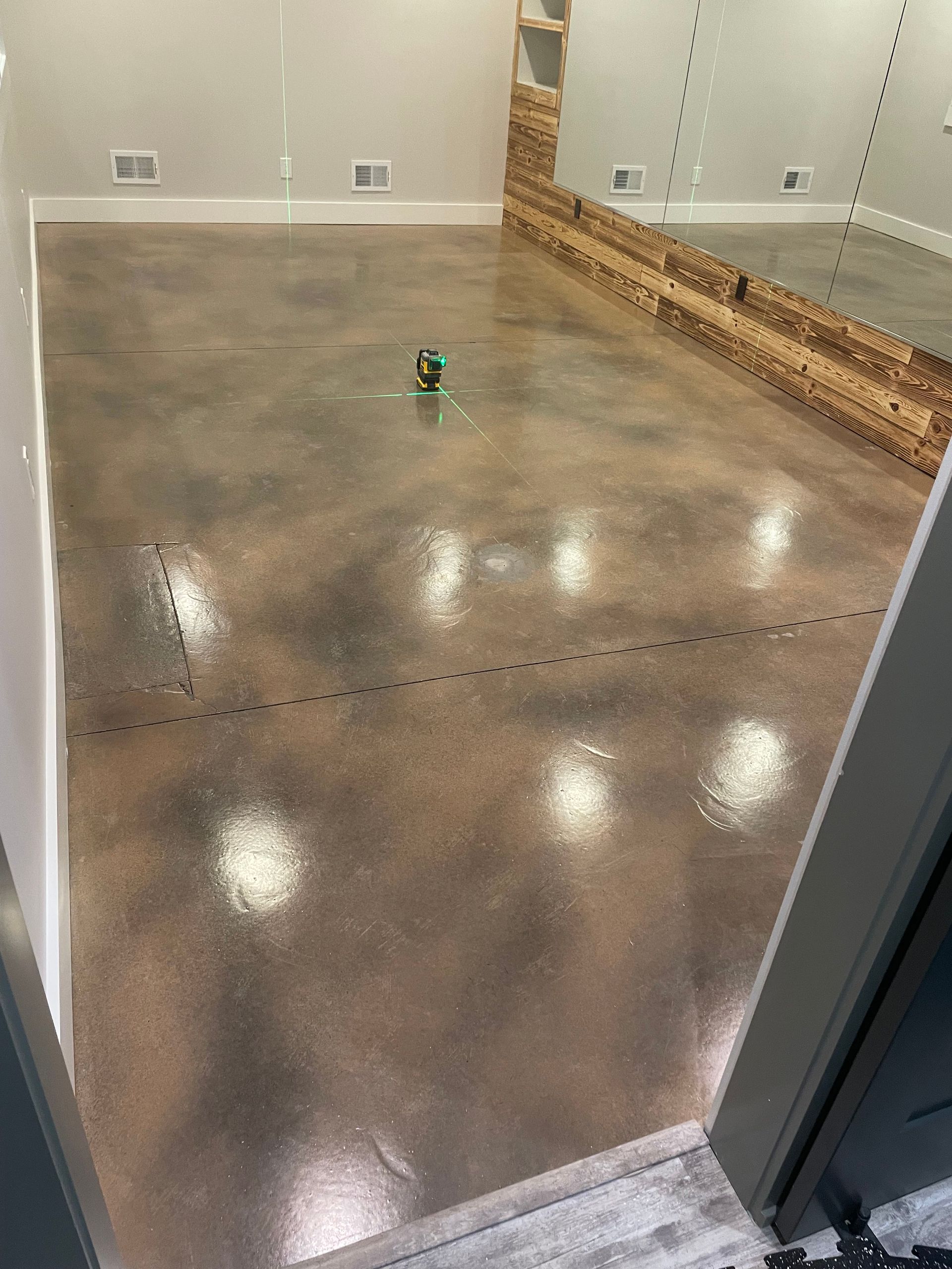 Shiny polished concrete floor in an empty room, with a small green object near center.