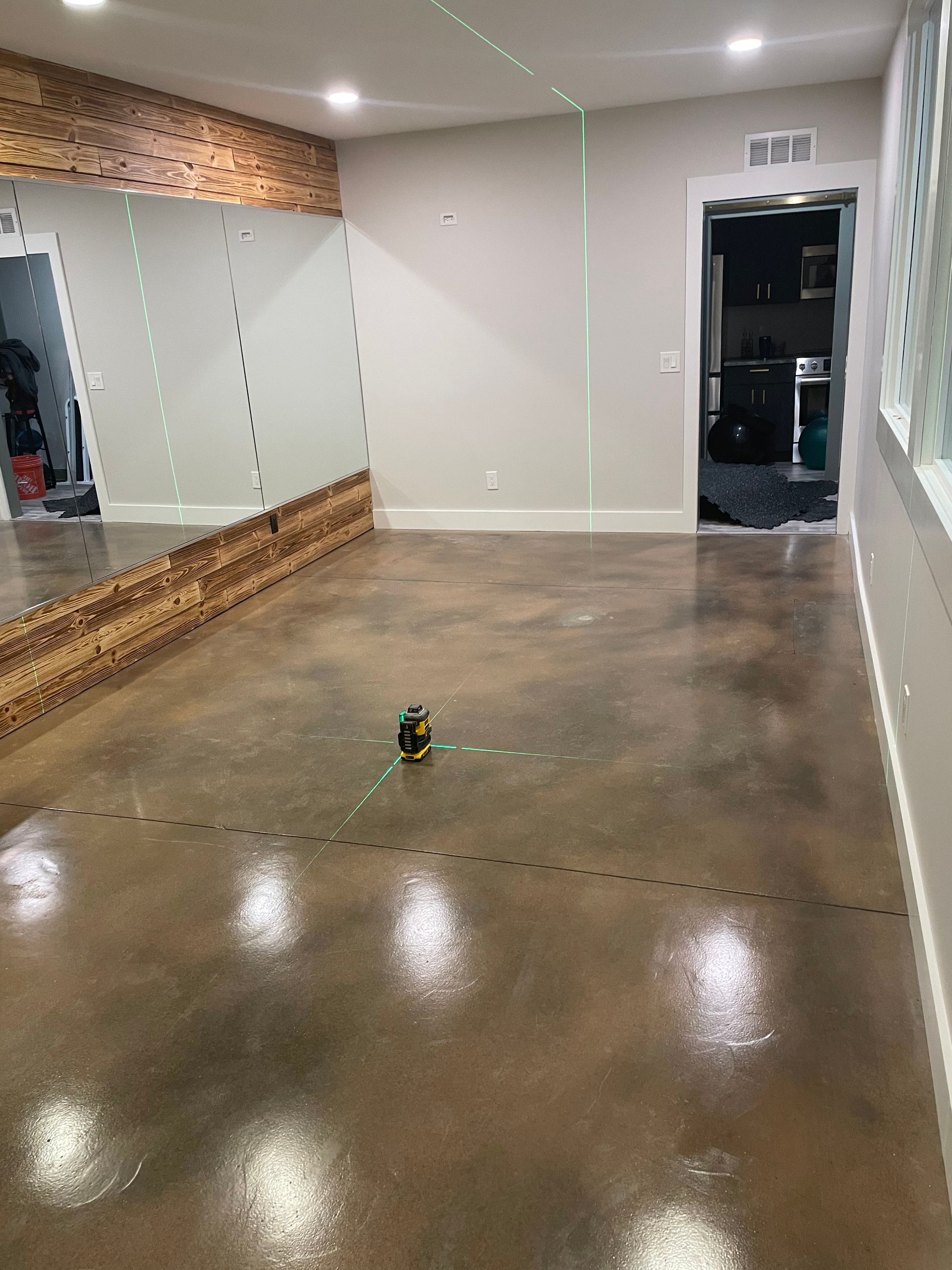 Empty dance studio with mirrored wall, polished concrete floor, and a small object in the center.