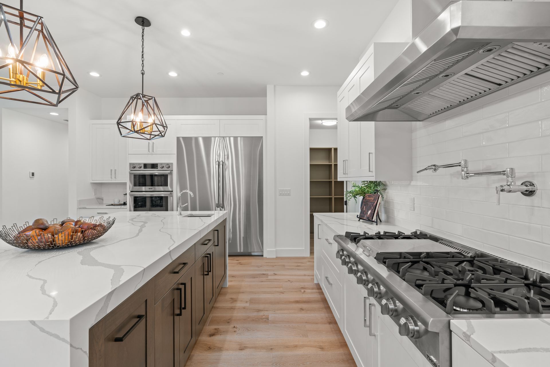 A kitchen with white cabinets , stainless steel appliances , a stove and a refrigerator.