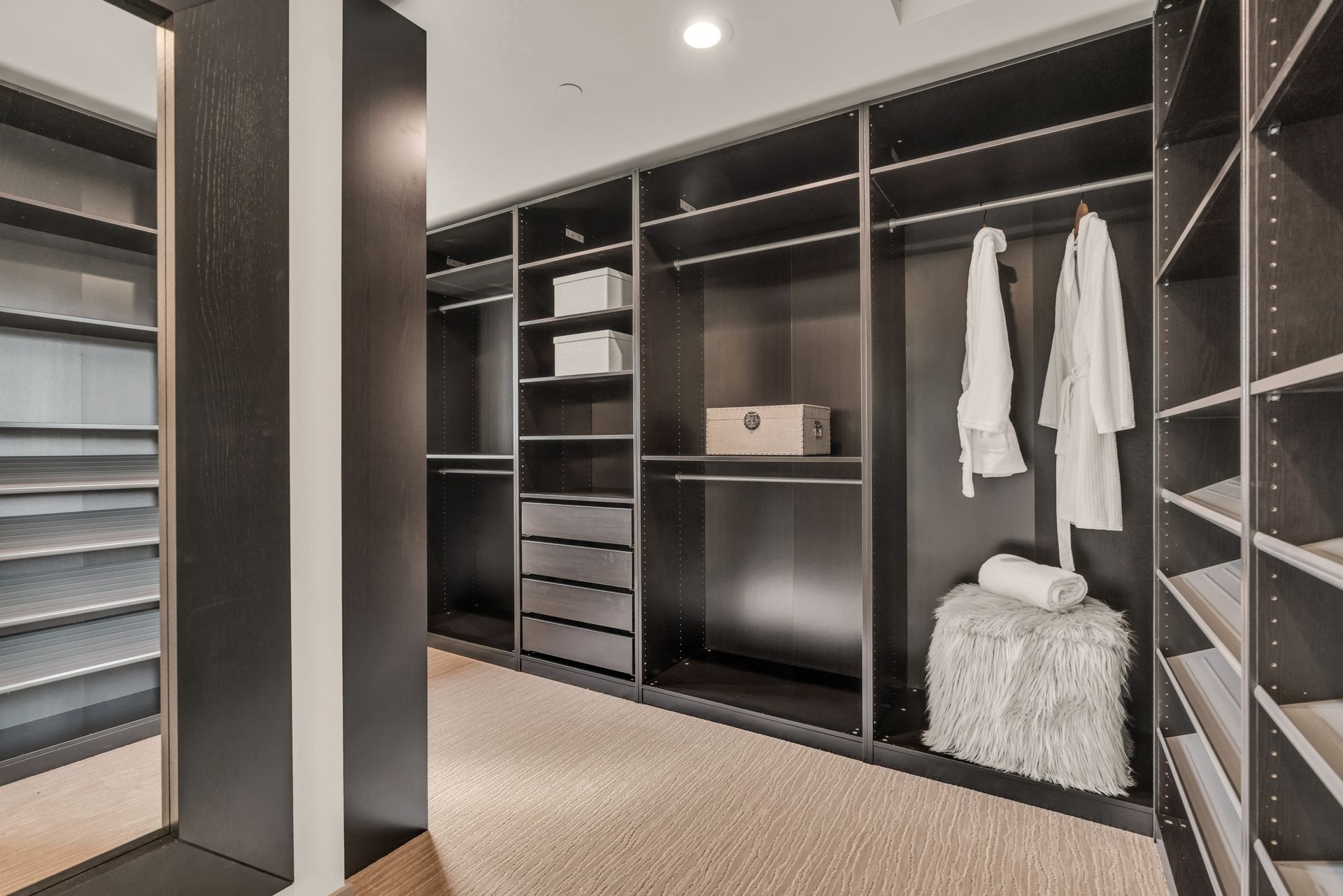A walk in closet with lots of shelves and a mirror