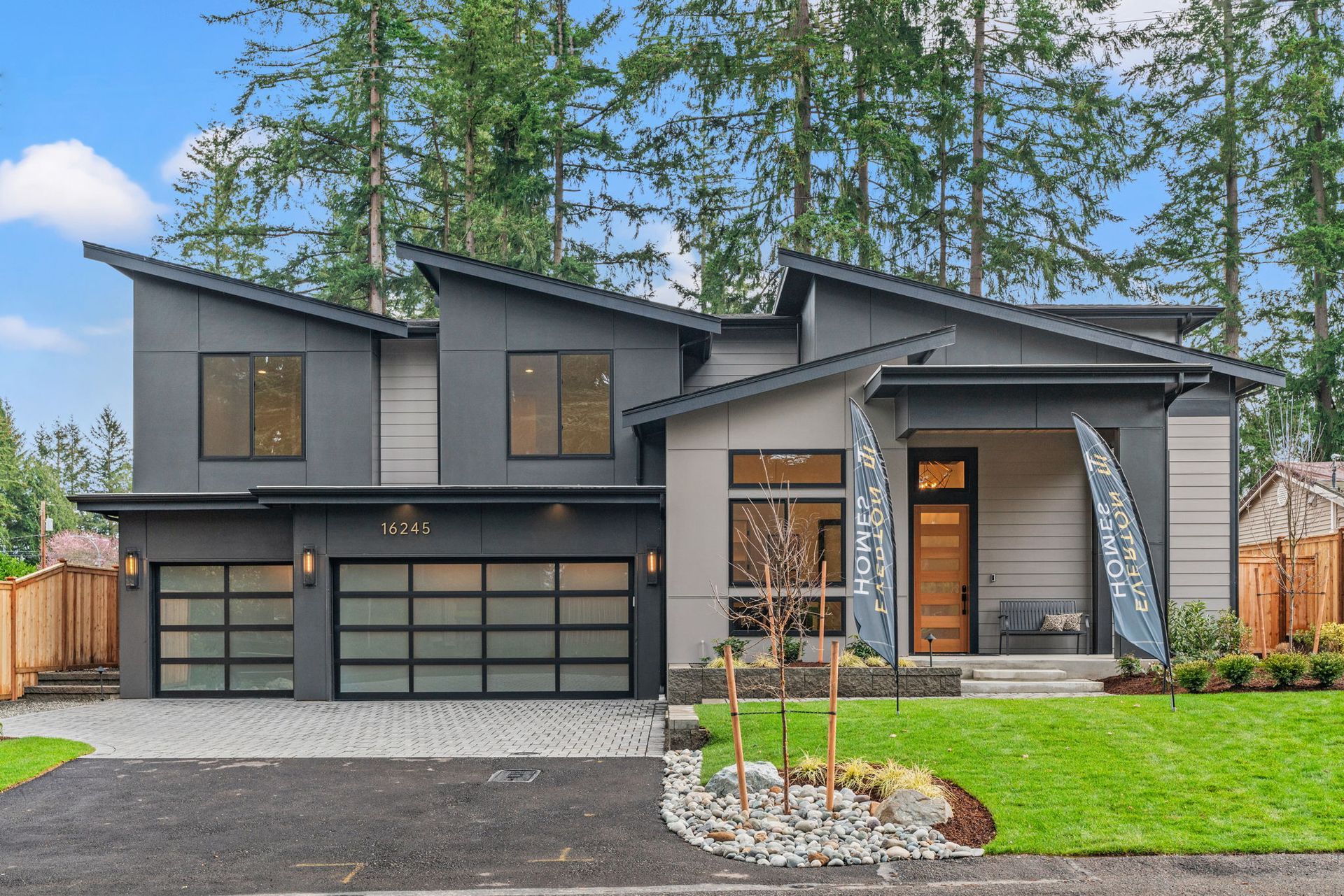 A modern house with a gray roof and a black garage door