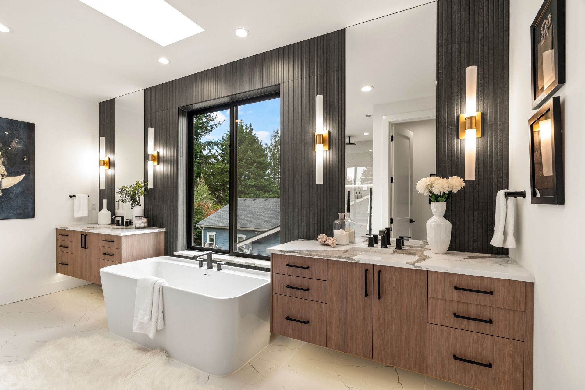 A luxury master bathroom with two sinks, a tub, and a large window.