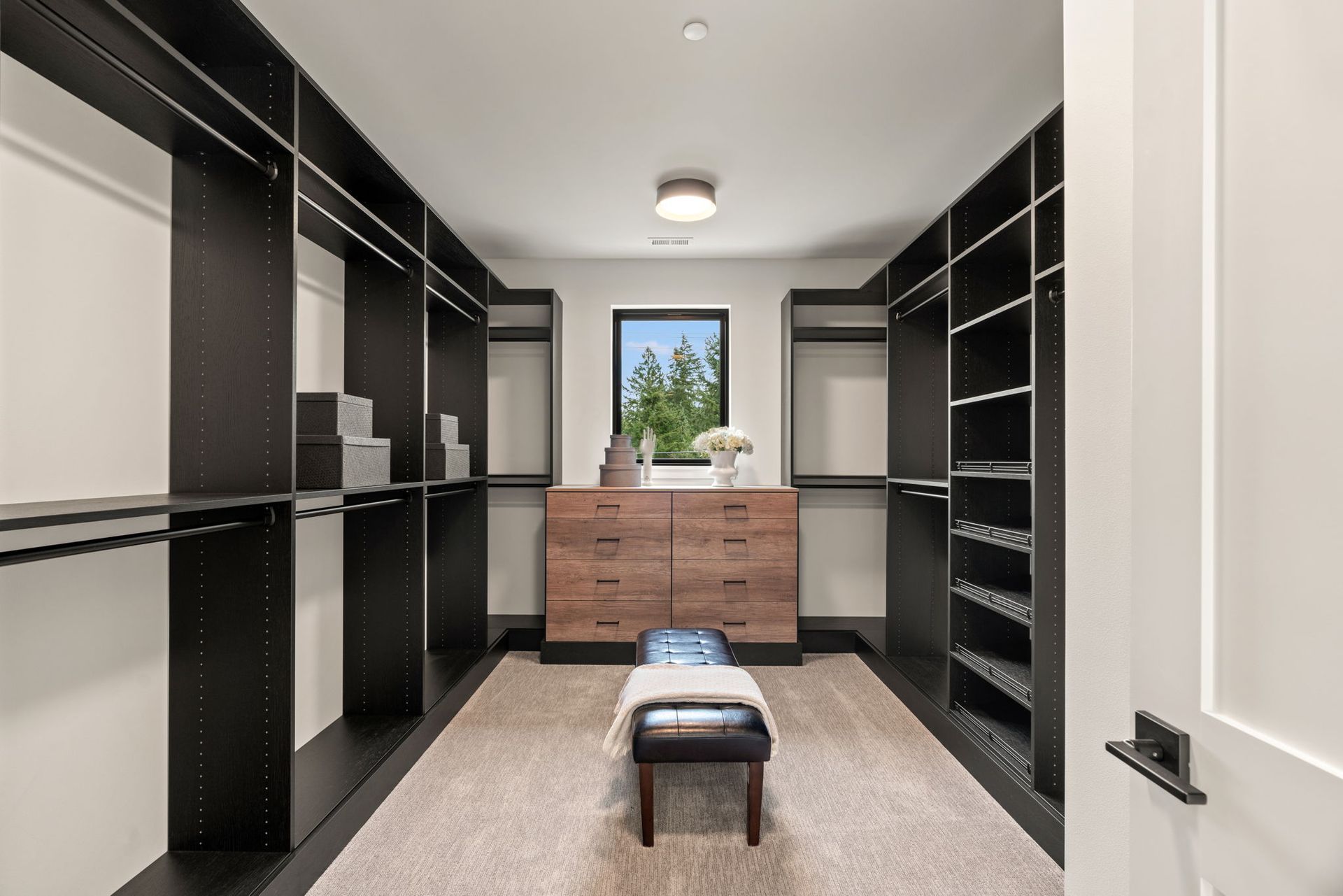 A walk in closet with lots of shelves and a bench.