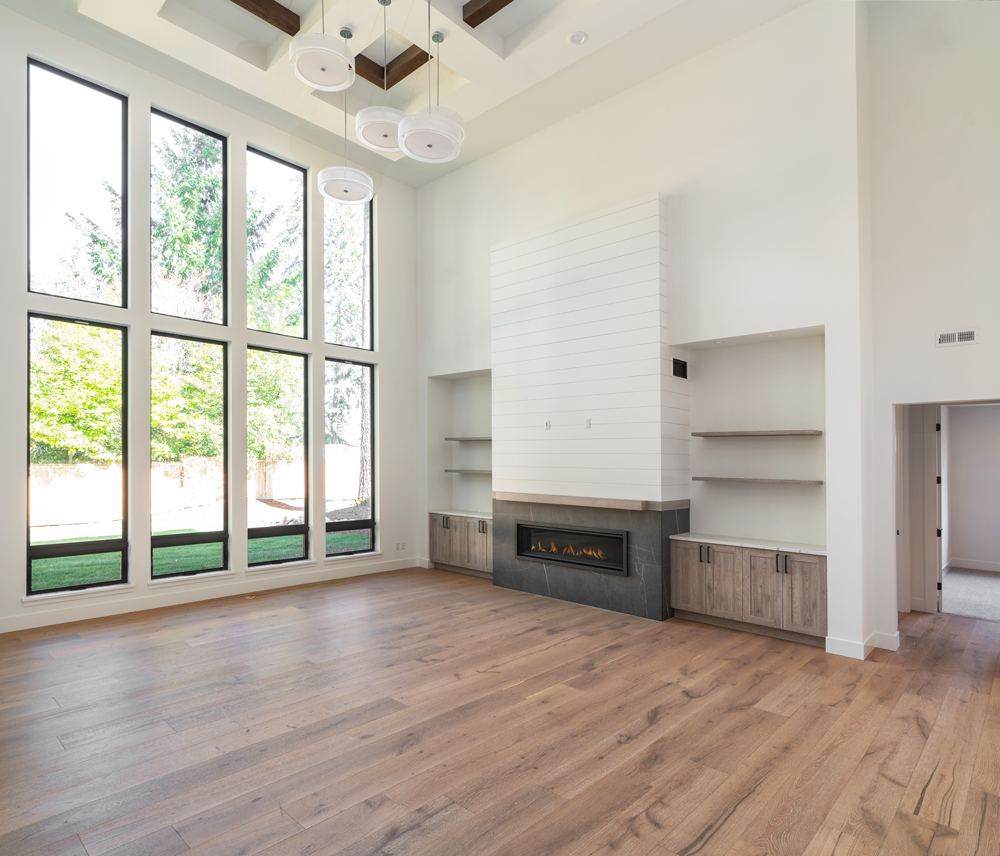 An empty living room with a fireplace and lots of windows