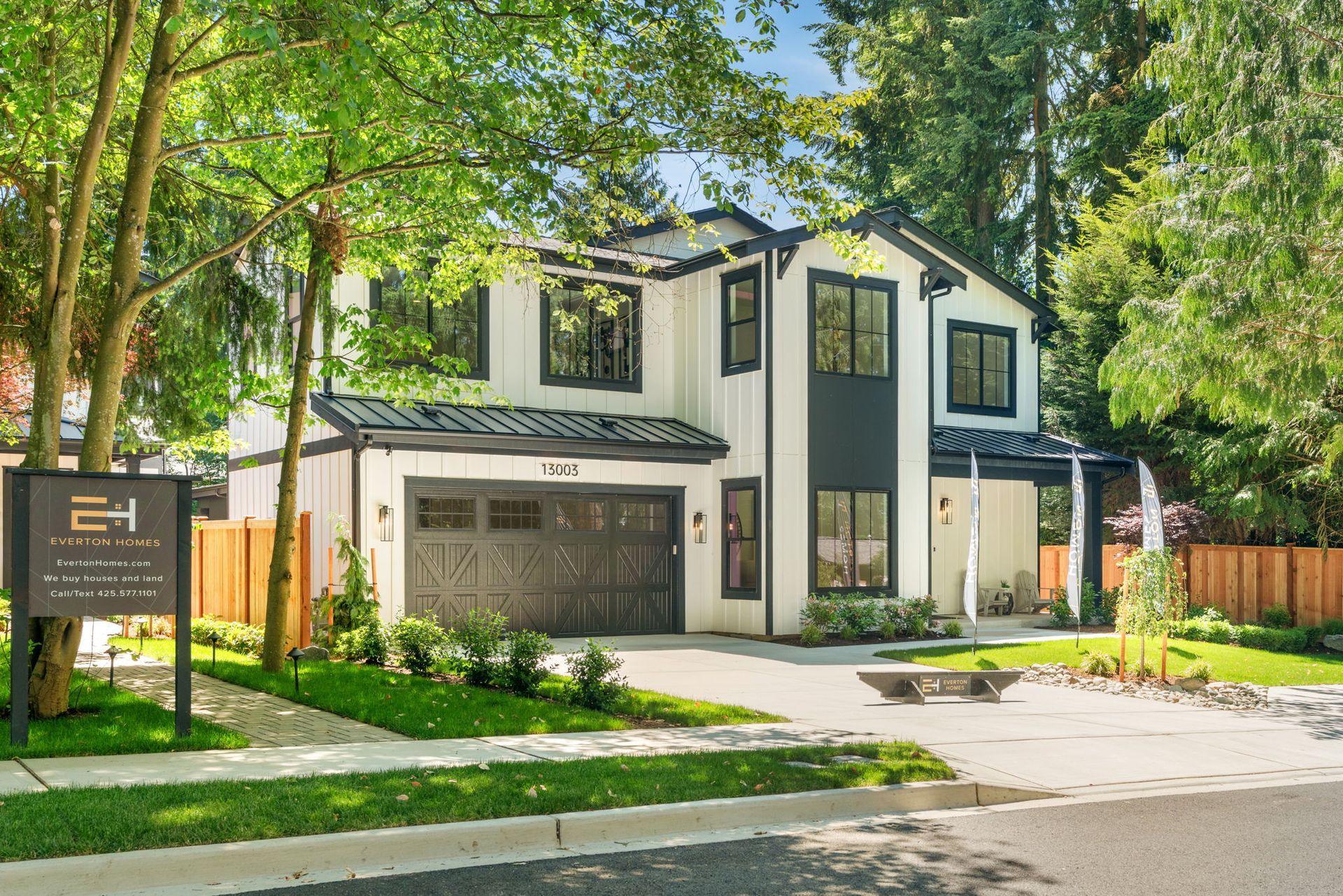 A large white house with a black garage door is for sale.