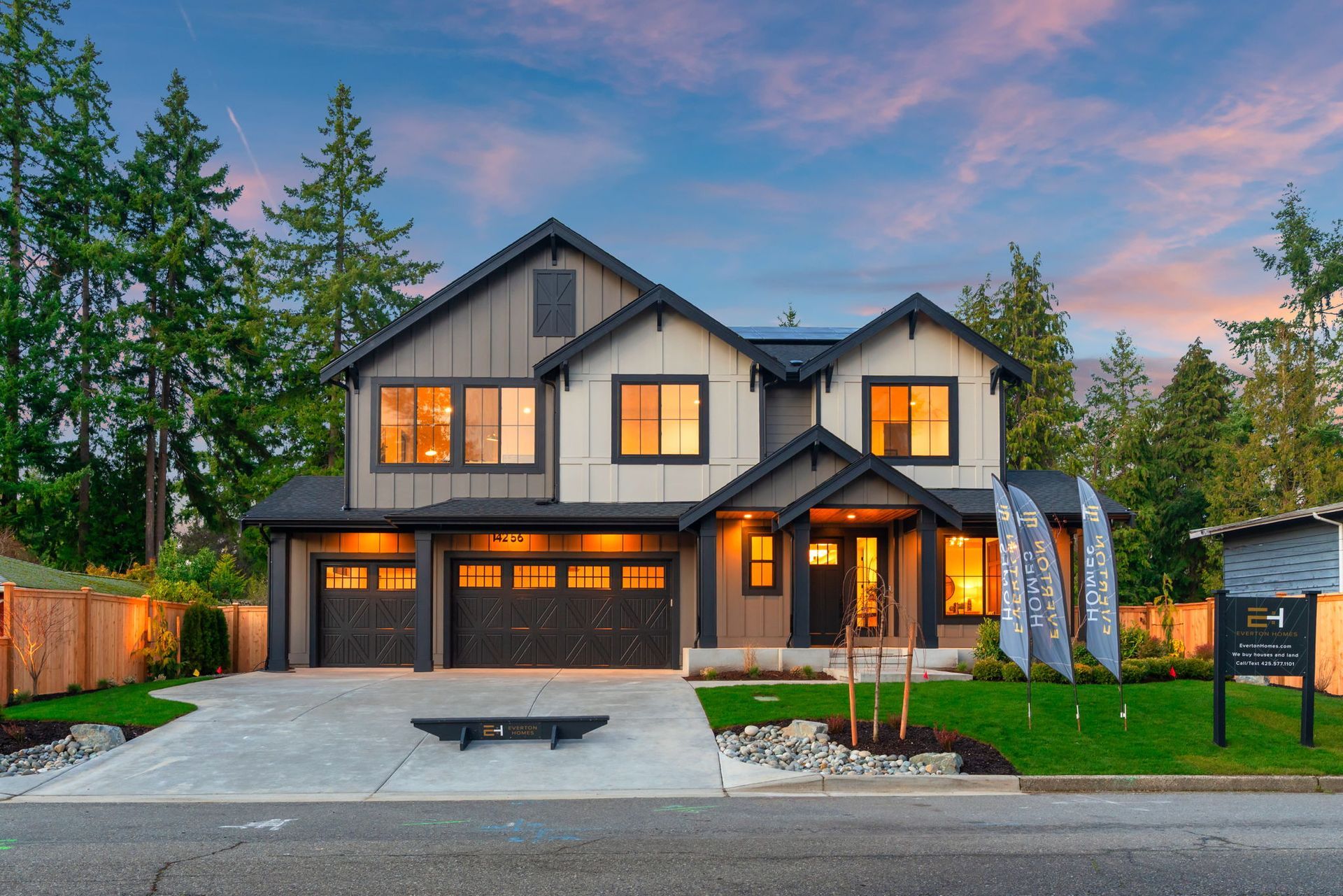 Two-story home with gray and tan siding, black trim, and a three-car garage, set against a sunset sky.