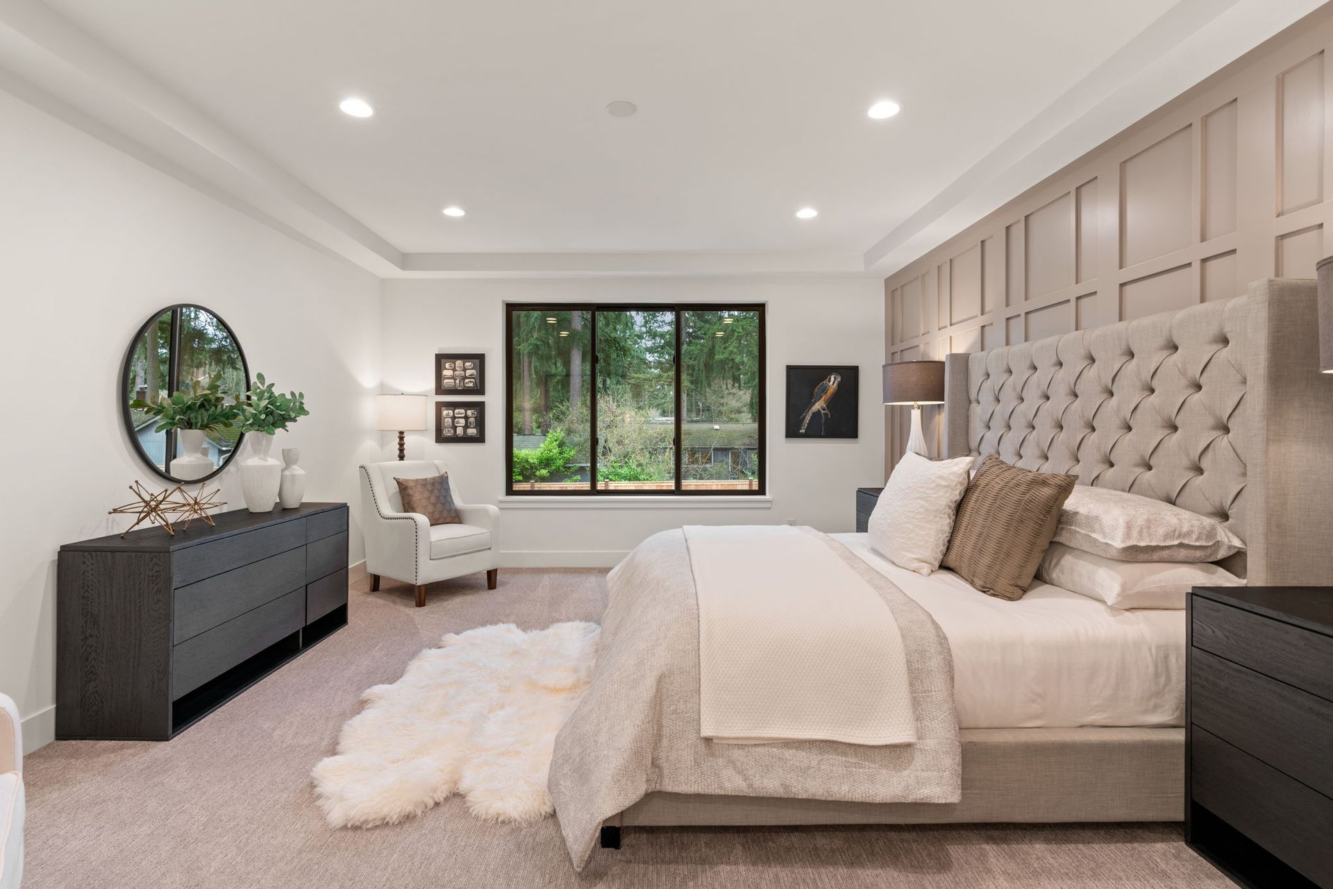 A bedroom with a bed, dresser, chair and mirror.