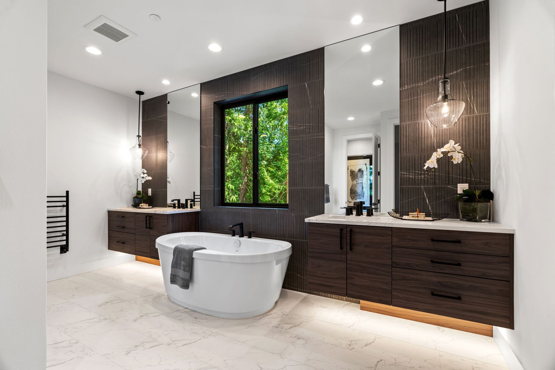 A stylish and spacious bathroom with a tub , sinks , mirrors and a window.
