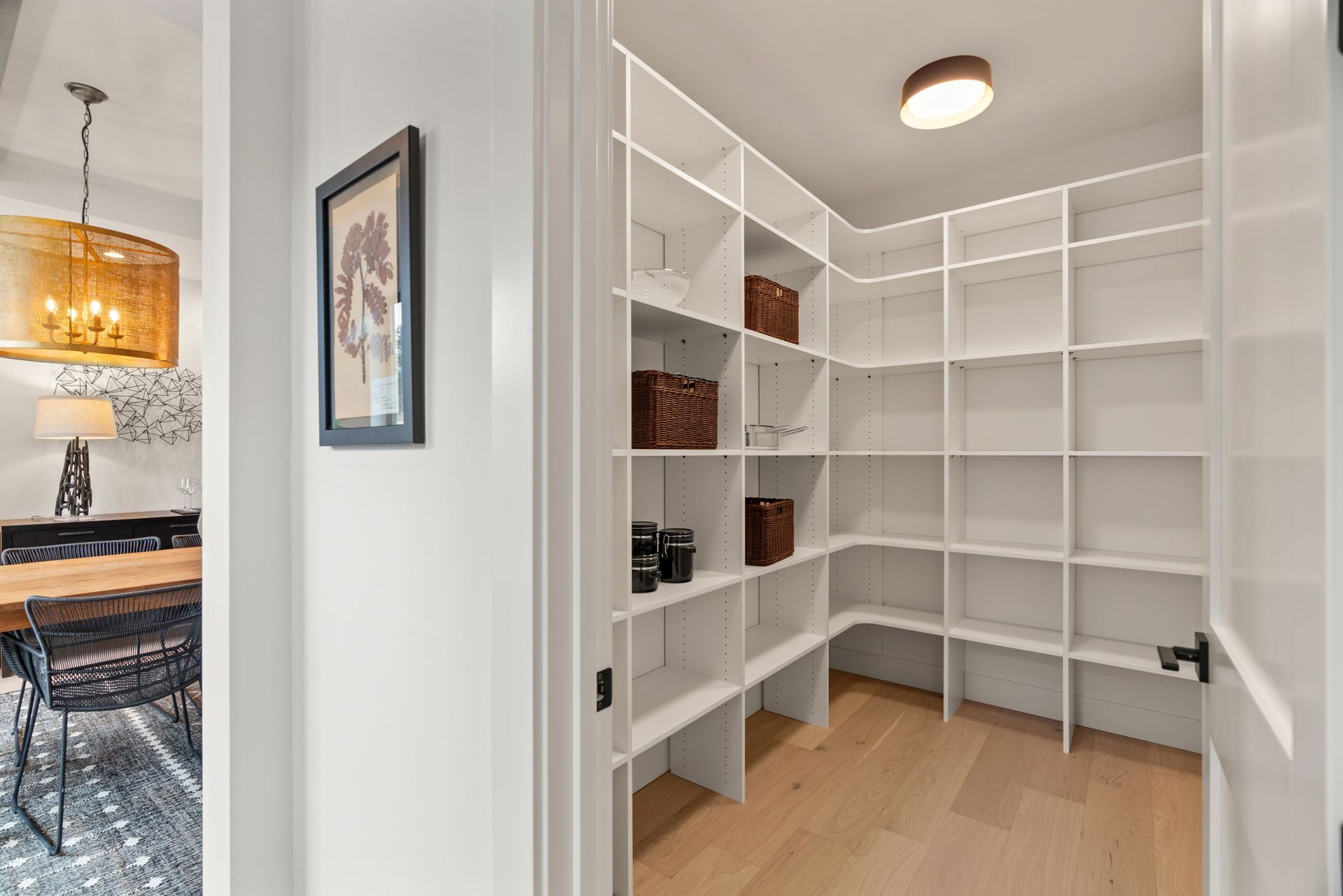 A walk in pantry with white shelves and wooden floors in a home.