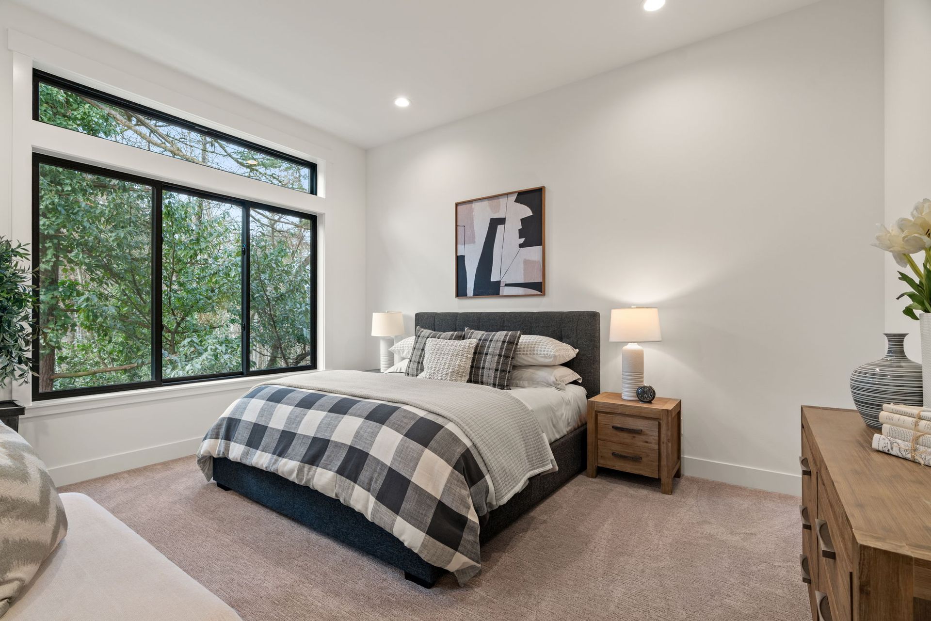 Modern bathroom with light wood cabinets, white walls, soaking tub, and a large window with a view.