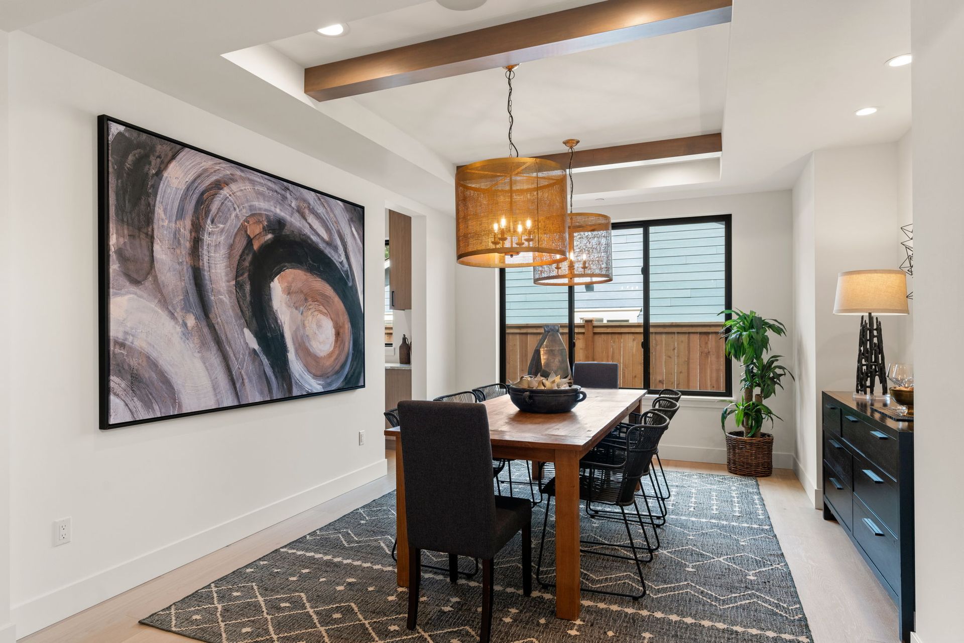 A dining room with a long table and chairs and a large painting on the wall.
