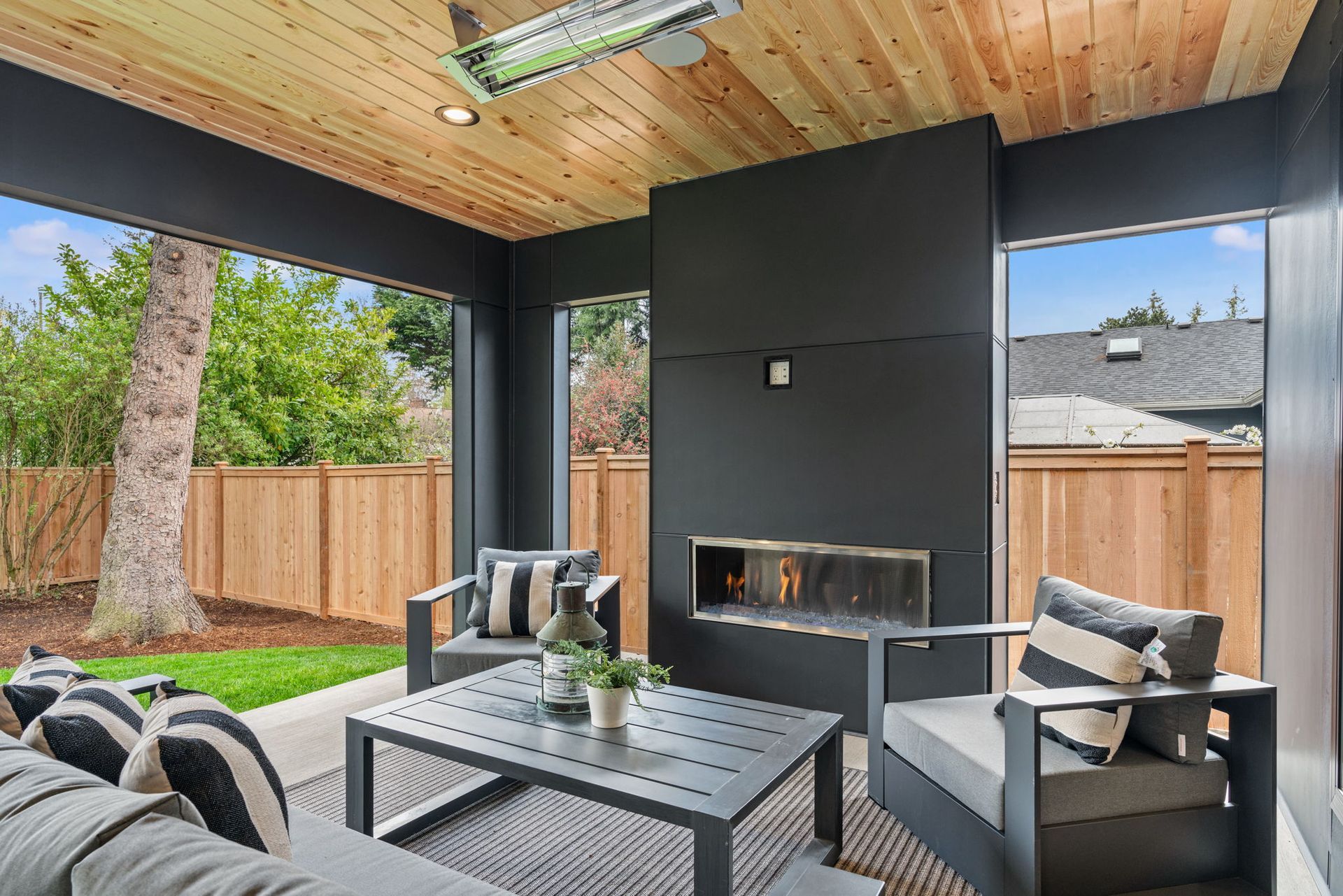 A covered patio with a fireplace and a couch and chairs.