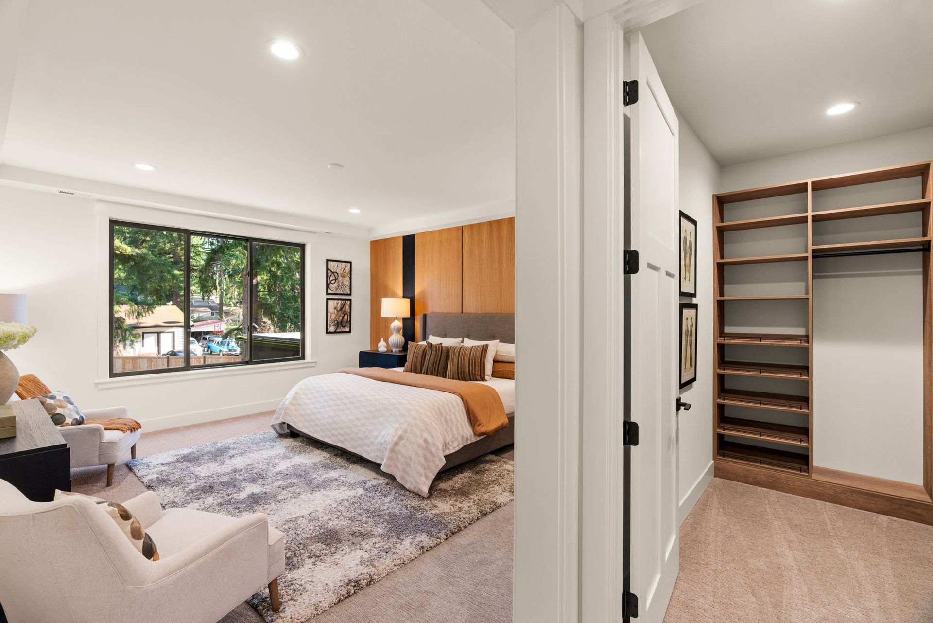 Bright entryway with wood floors, recessed lighting, and wooden beams. A partially open black door reveals a long hallway.