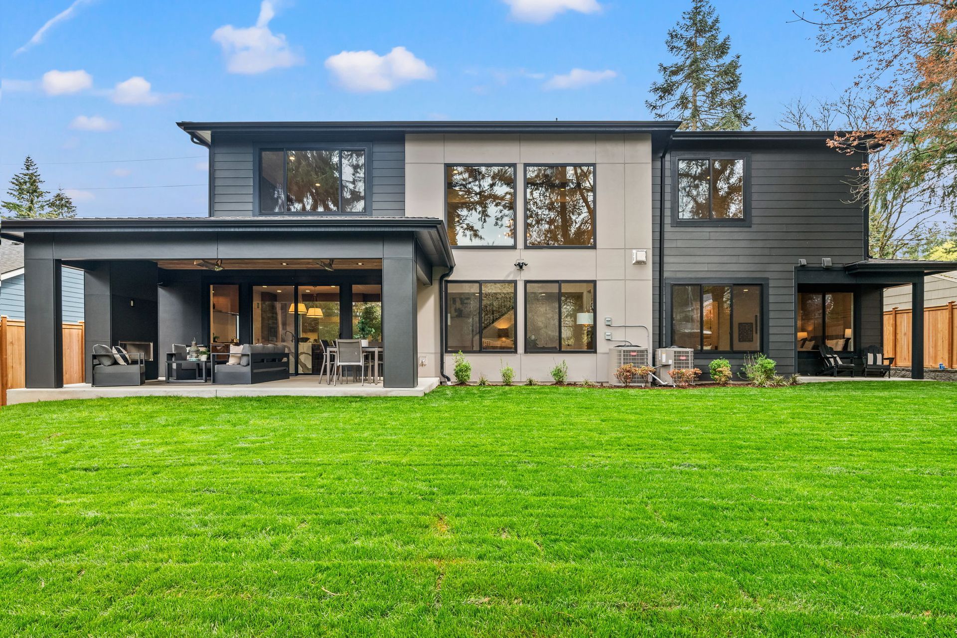 The back of a large house with a large lawn in front of it.