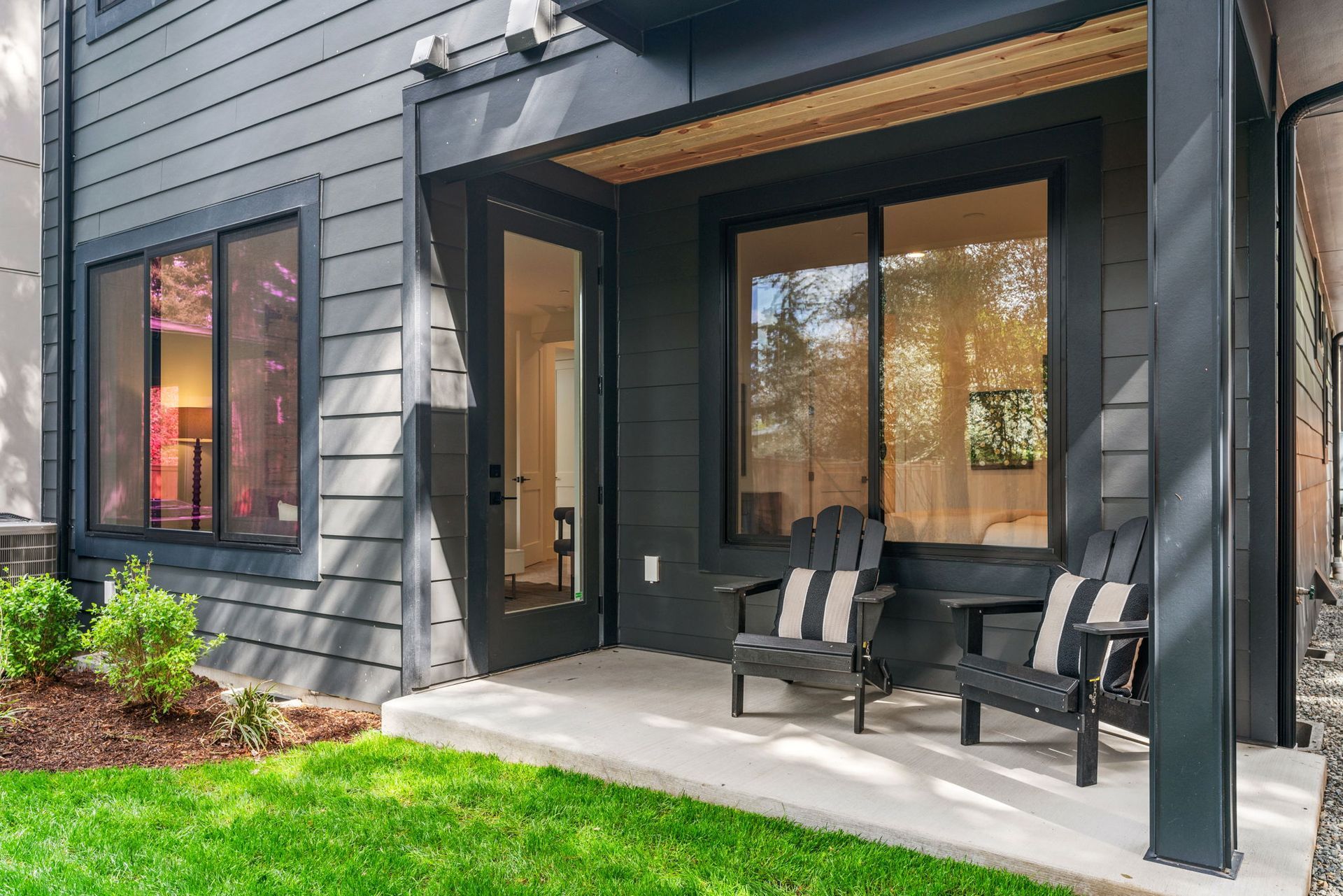 A covered patio with a fireplace and a couch and chairs.
