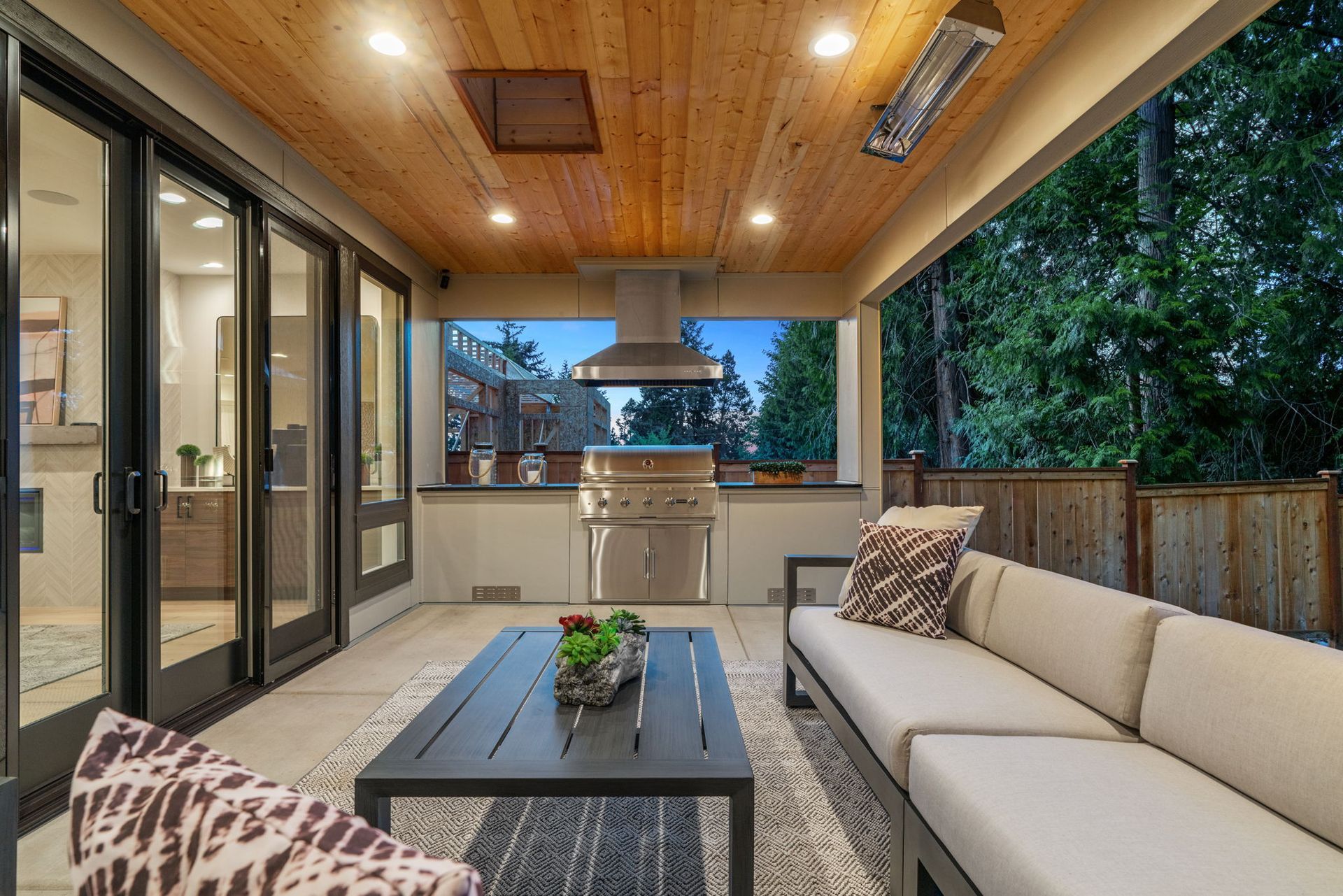 A patio with a couch , table , chairs and a grill.