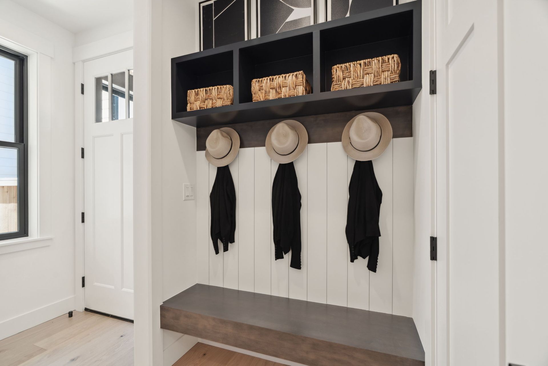 There are three hats hanging on the wall in the hallway.