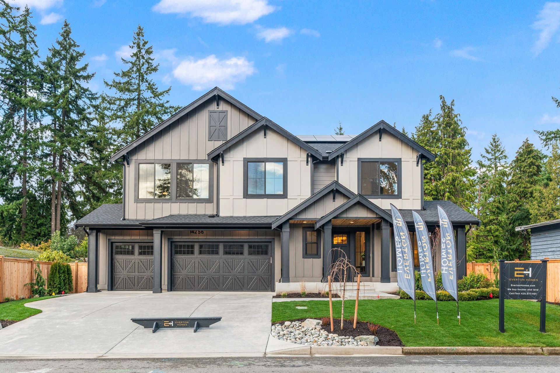 Modern two-story house with gray and brown exterior, two-car garage, and a well-manicured lawn.