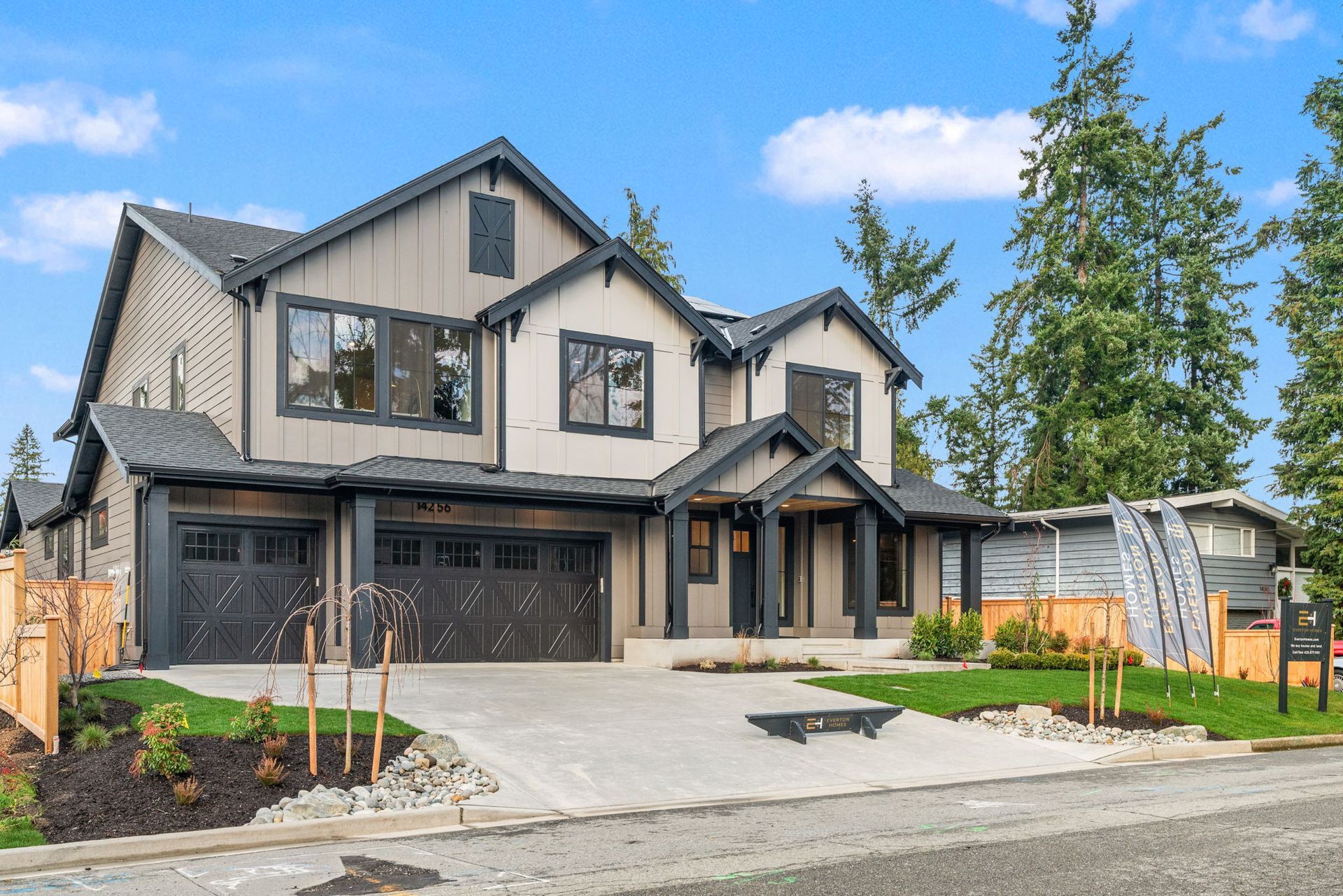 Two-story house with black and gray exterior, driveway, green lawn.