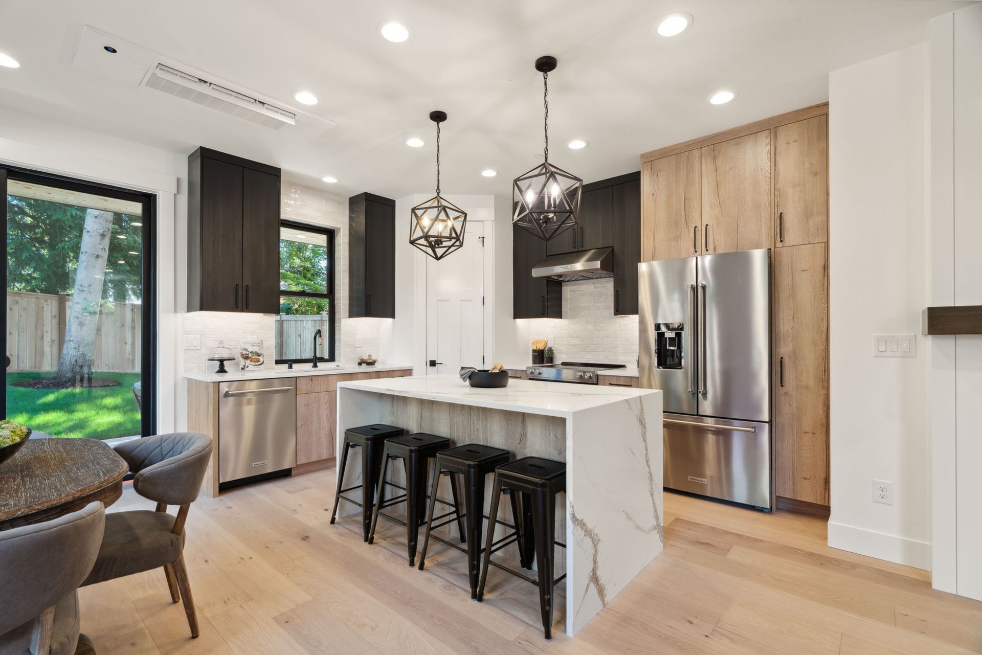 A kitchen with a large island , stools , a refrigerator and a fireplace.