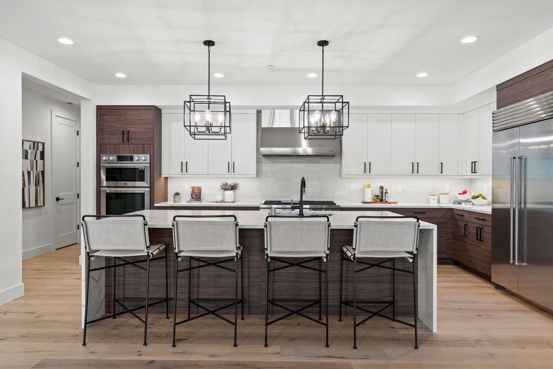 A modern kitchen with white cabinets , wooden floors , stainless steel appliances and a large island.