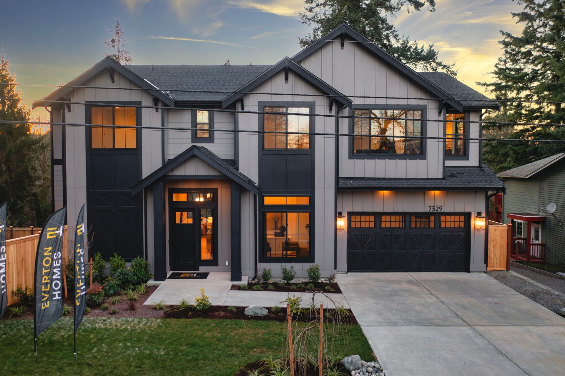 Modern two-story house with gray and black exterior, front yard, and driveway.