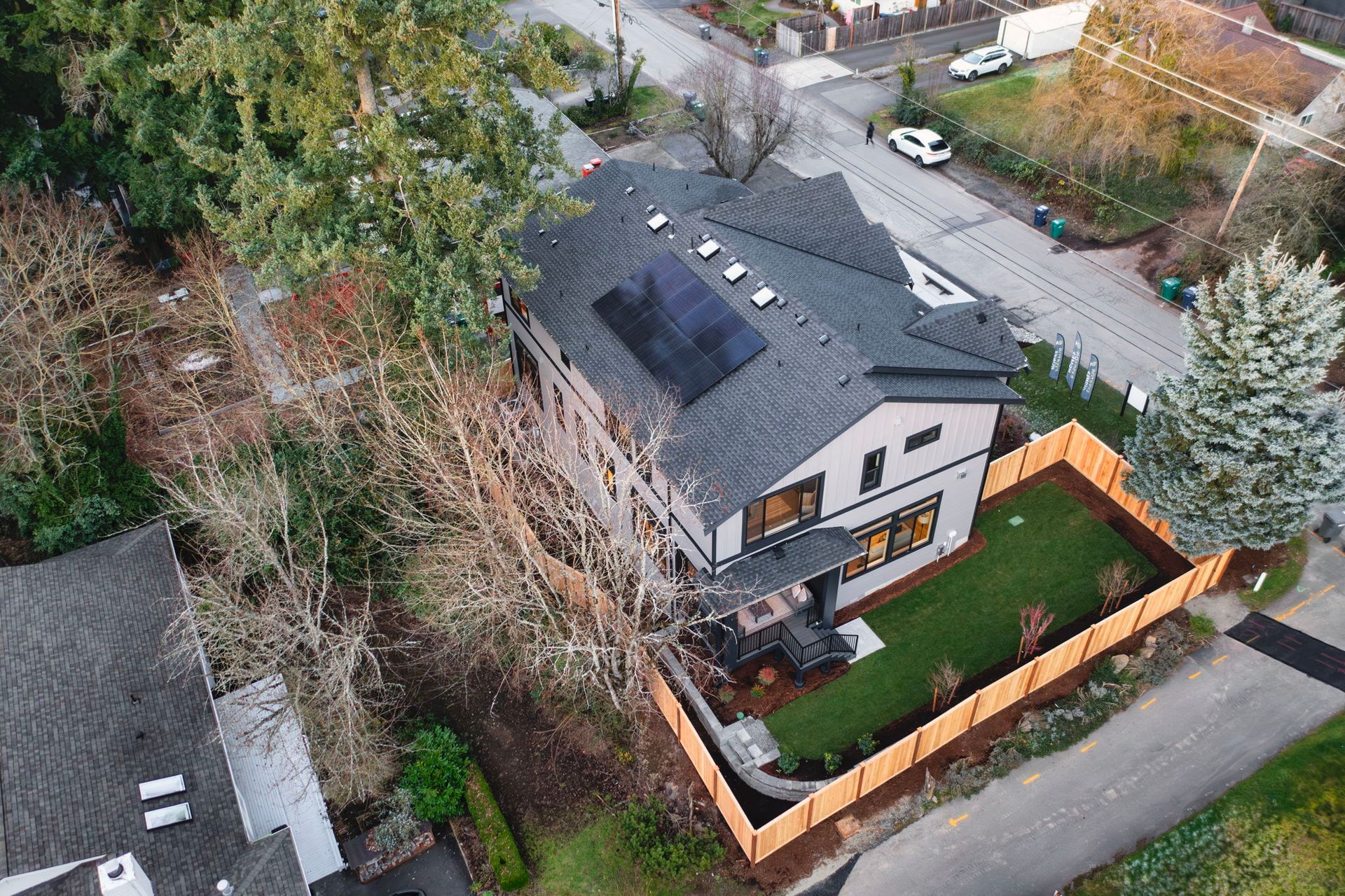 Dining room with table, chairs, rug, and large windows overlooking trees.