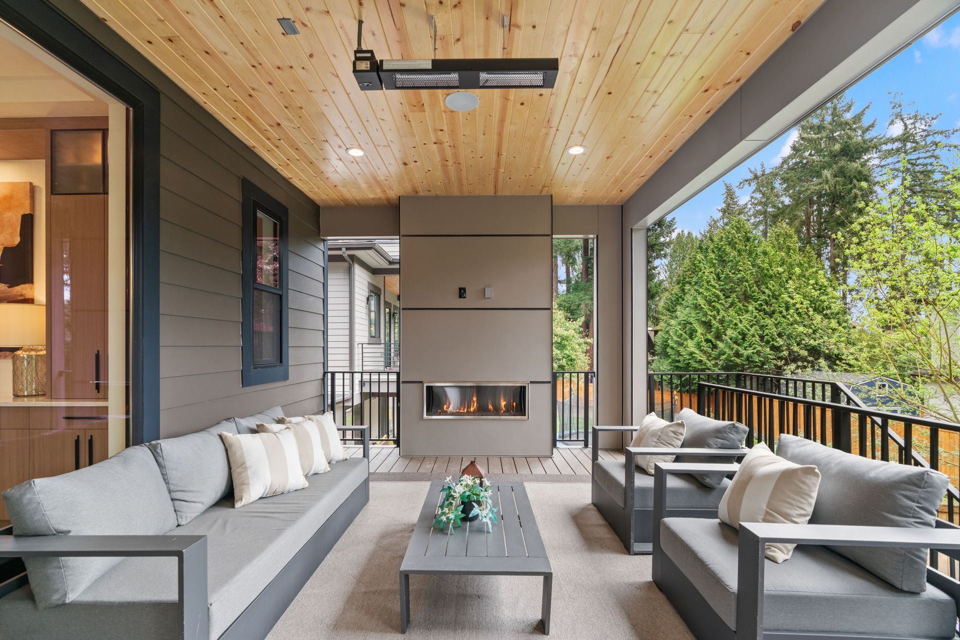A modern game room featuring a ping pong table, light wood floors, black paneling, wall art, and glass sliding doors.