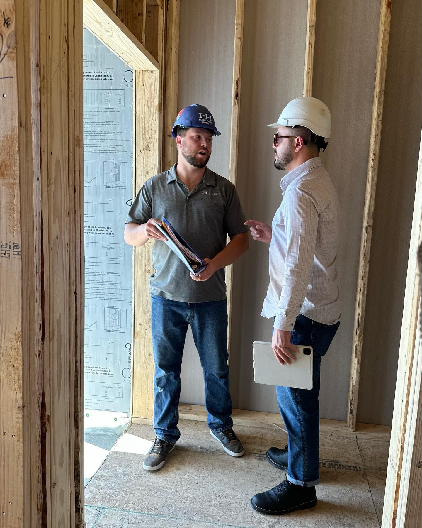 Two men in hard hats are standing next to each other in a room.