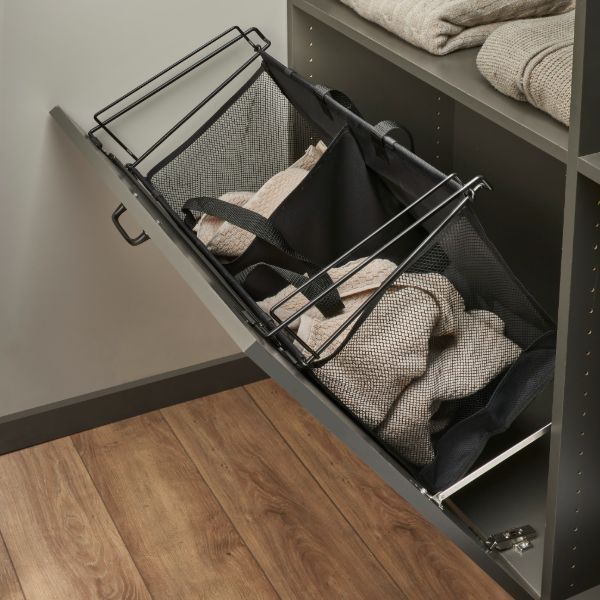 A laundry basket in a closet filled with clothes