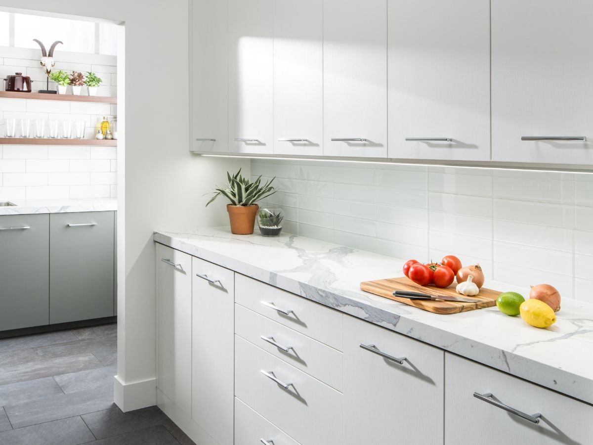 A kitchen with white cabinets and a cutting board with fruit on it.