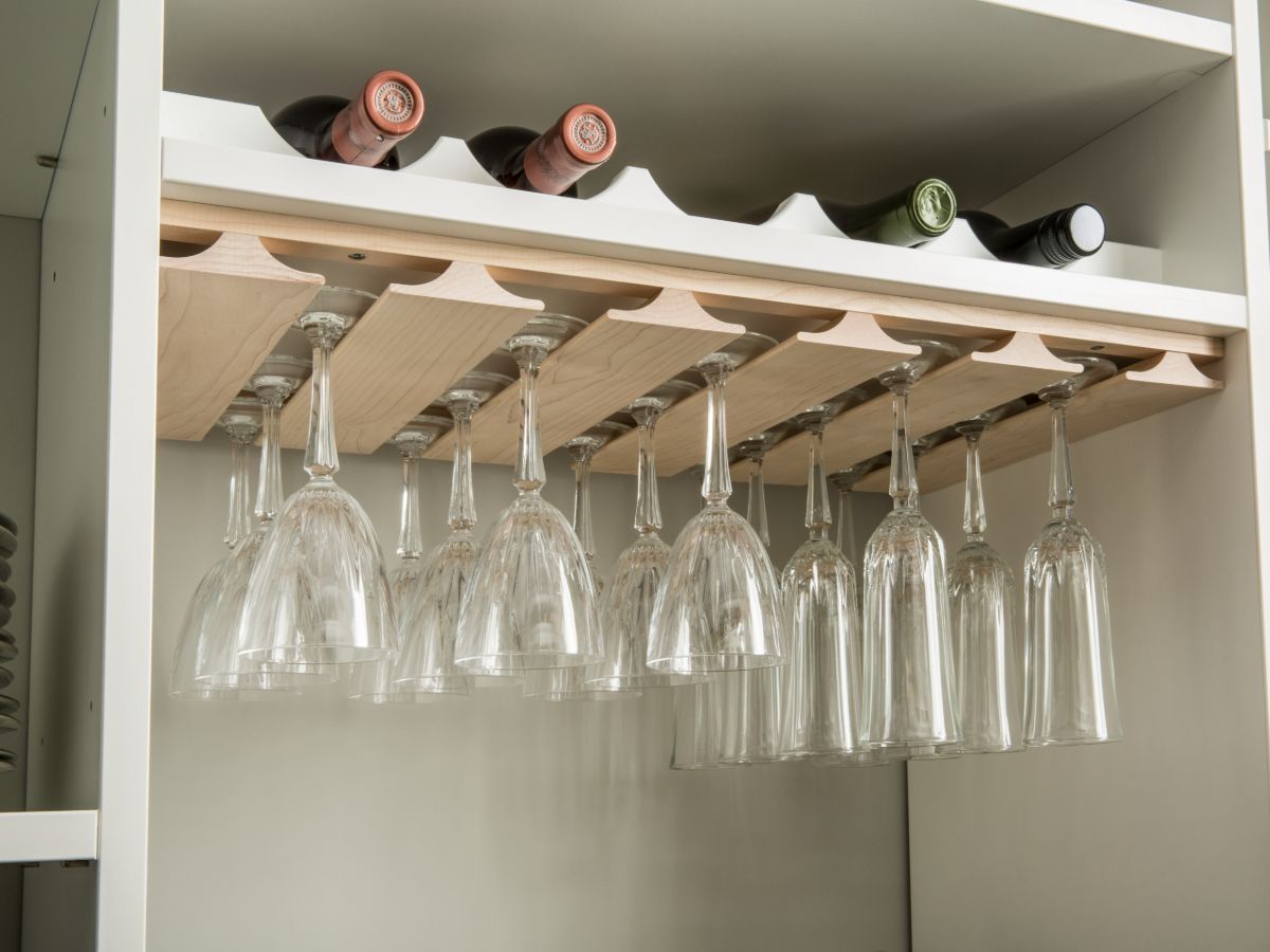 A wine rack with wine bottles and wine glasses hanging from it.