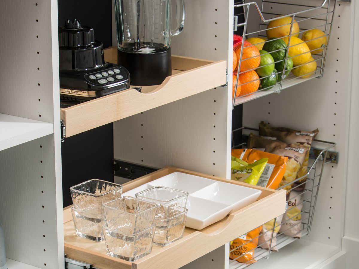 A pantry with a blender , fruits and vegetables on the shelves.