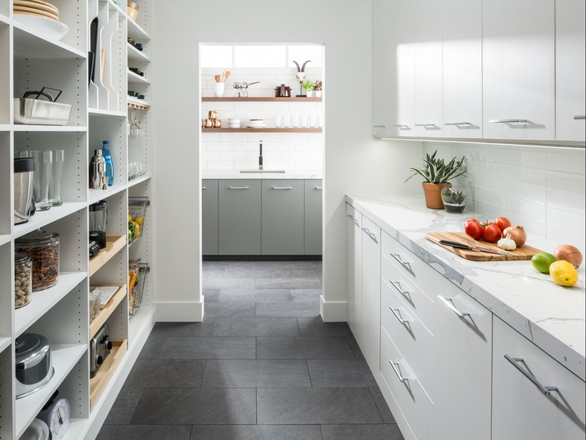 A kitchen with white cabinets and a walk in pantry filled with fruits and vegetables.